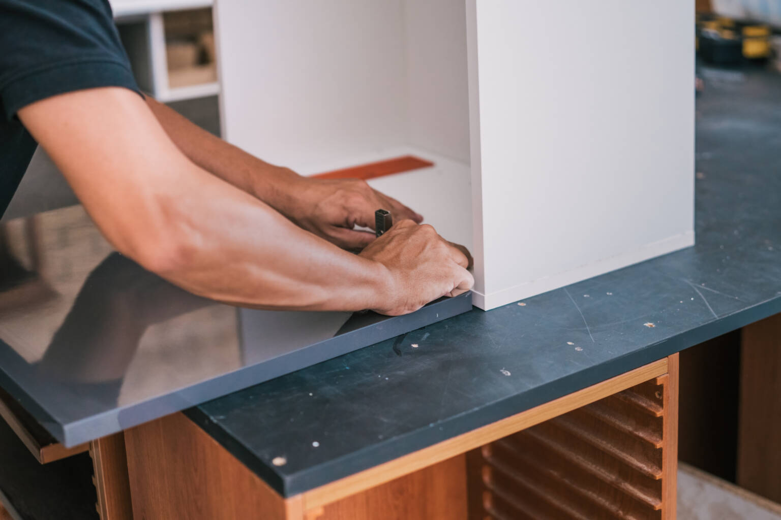 Craftsman fixing a hinge on kitchen cabinet surface — custom kitchen workmanship Malaysia