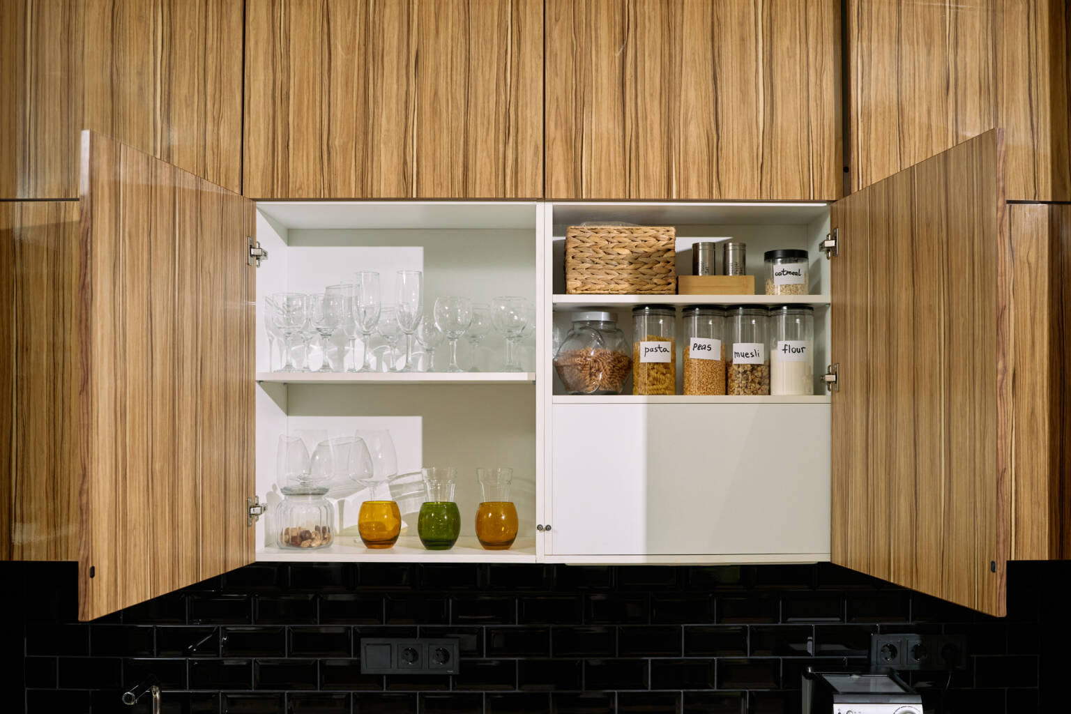 Kitchen cabinet with glass doors displaying glassware and food storage