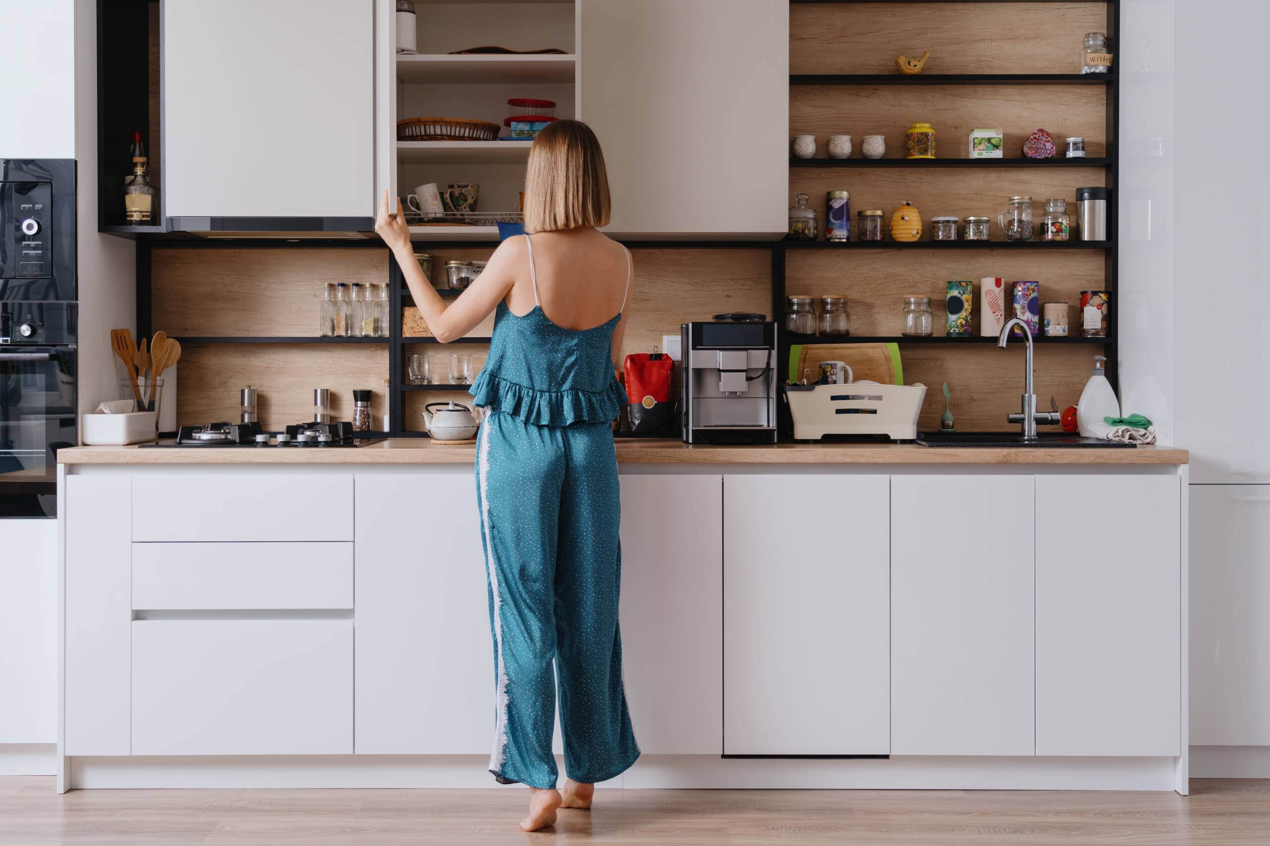 Woman in kitchen looking for a cup — kitchen cabinet price guide Malaysia 2026